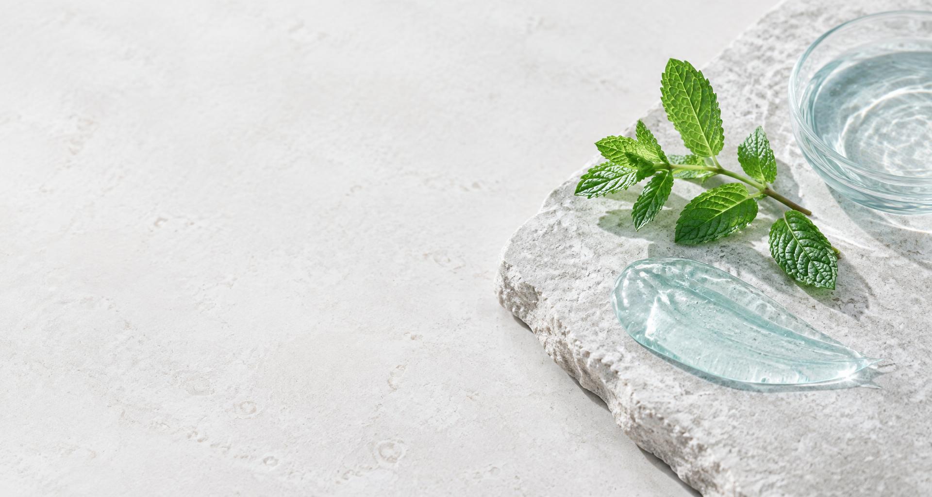 Fresh mint and a transparent gel on a light stone surface